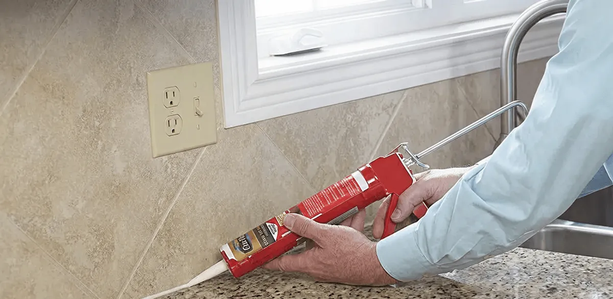 Handyman applying caulk along a kitchen backsplash and countertop seam in Scottsdale, AZ